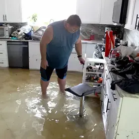 Flooded kitchen with man trying to clean it. Photo credit: Joe Raedle