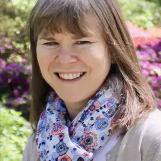 Smiling woman in floral scarf surrounded by foliage