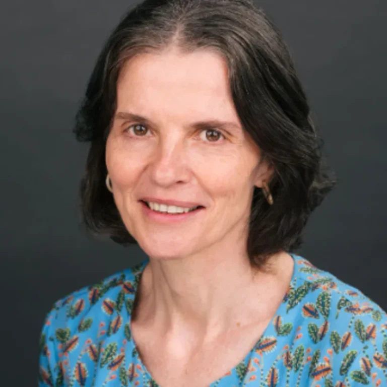 Closely framed headshot of Maria Uriarte in a green patterned shirt.