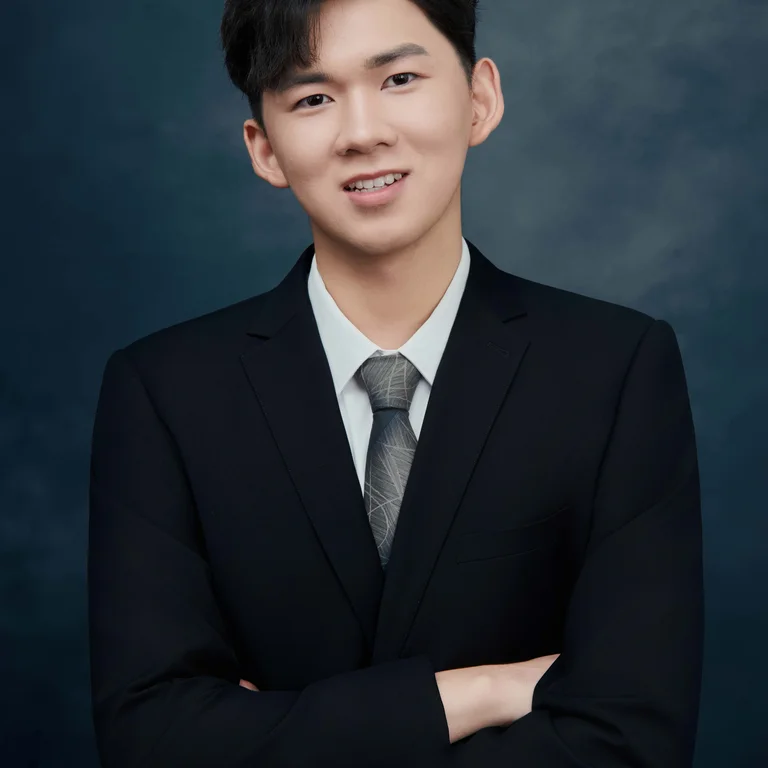 professional headshot of Joe Wang cross armed wearing black suit, white dress shirt, and grey tie