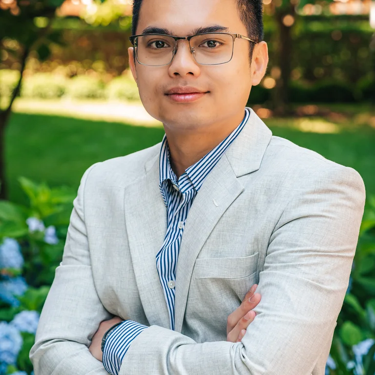 professional headshot of Yosafat Tambunan cross armed wearing glasses, light grey suit and blue dress shirt