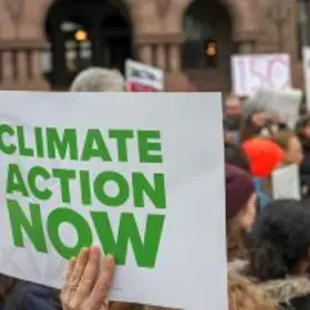 Protester holding sign that reads "Climate Action Now"