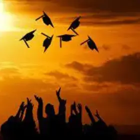 silhouette of six students throwing graduation caps in the air