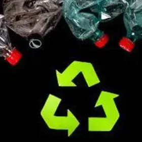 Top view of plastic bottles above recycling symbol on a black background