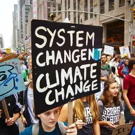 Protester holding sign that reads "System change, Not Climate Change"