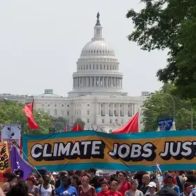 Protestor at DC Climate March holding banner that reads "Climate Jobs Justice"