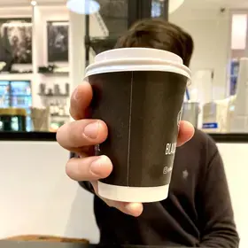 A Columbia student holds a disposable coffee cup.