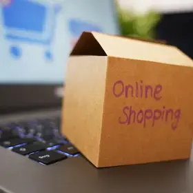 Small cardboard box with the text "Online Shopping" sitting on an open laptop.