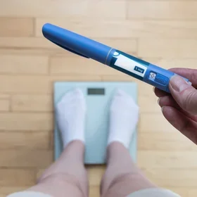 Woman weighs herself and holds Ozempic in her hand ,iStock credit: Carolina Rudah