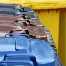 Image of garbage can lids: black for trash, brown for organic waste, and blue for recycling.