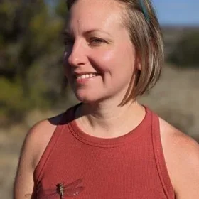 Candid photo of Bekka Brodie standing outdoors in a red tank top.