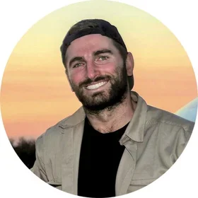 Jay Schoen stands outdoors in front of a sunset.