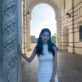 Zuoqing (Lenita) Lyu smiling in a white dress standing under an archway