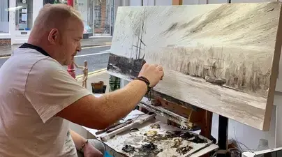 Veteran artist Adrian Wright paints a picture in his studio.