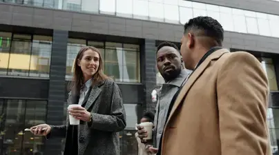 A photo of two men and one woman in professional clothing talking outside.