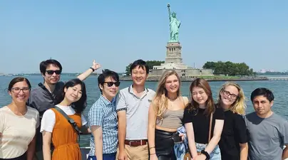 Students standing with the Statue of Liberty behind them. 